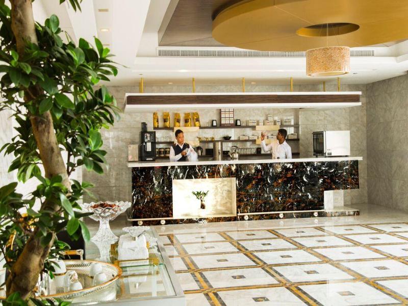 占奈萨拉卜塔酒店 阿布扎比 外观 照片 The photo depicts a modern reception area or lobby, featuring a stylish check-in counter made of dark marble with a gold accent. Behind the counter, two staff members are engaged in work, likely attending to guests. The area is well-lit and has conte